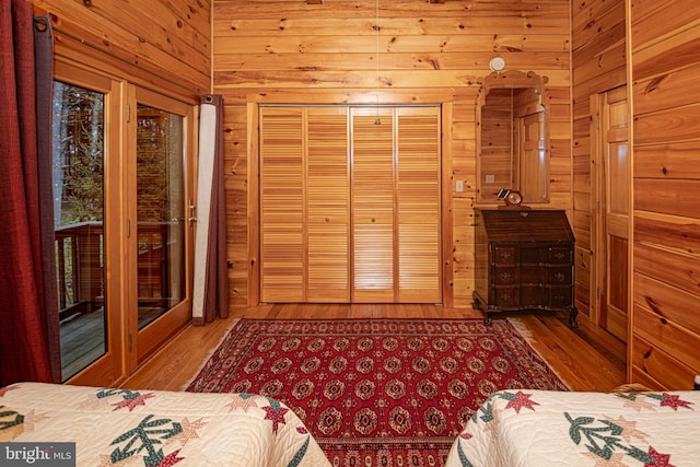 unfurnished bedroom featuring wood finished floors, wooden walls, and access to outside