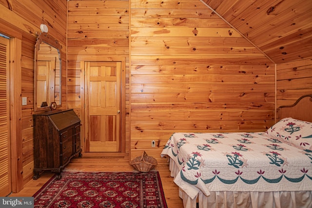 bedroom with lofted ceiling, wooden walls, light wood-type flooring, and wood ceiling