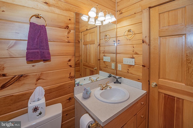 half bath with vanity, wooden walls, and toilet