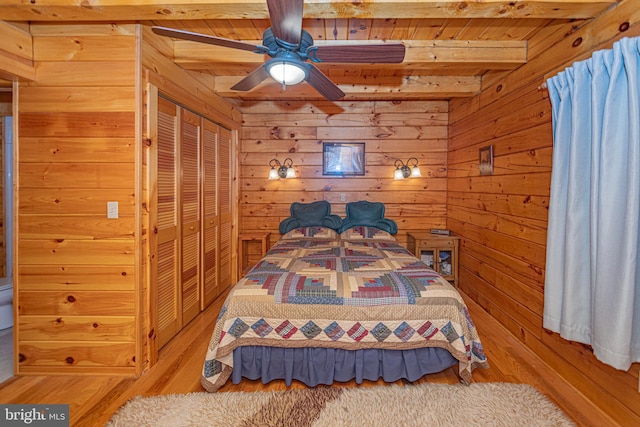 bedroom featuring wooden ceiling, wooden walls, wood finished floors, and beamed ceiling