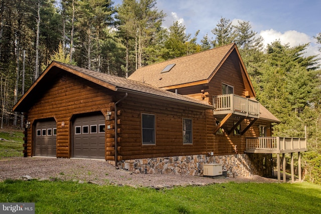 view of property exterior featuring log siding, roof with shingles, a balcony, a yard, and a wooden deck
