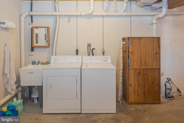 washroom featuring washer and dryer, laundry area, concrete block wall, and a sink