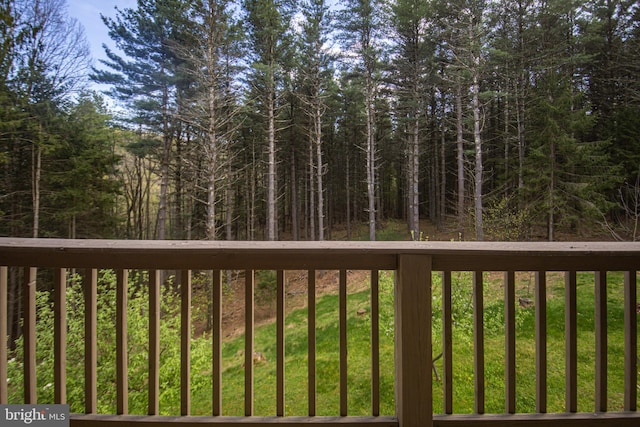 wooden terrace with a yard and a view of trees
