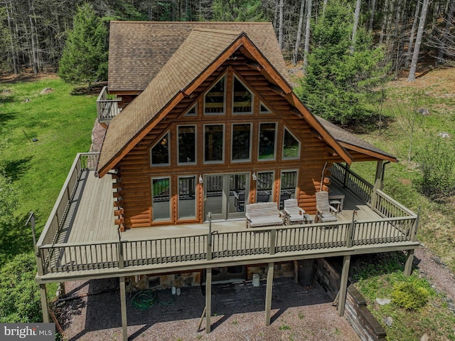 back of house featuring log siding, roof with shingles, and a deck