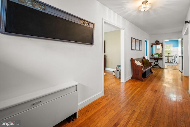 corridor featuring wood-type flooring and baseboards