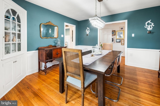 dining room featuring wainscoting, a chandelier, and wood finished floors