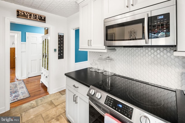 kitchen featuring appliances with stainless steel finishes, backsplash, white cabinetry, and light tile patterned flooring