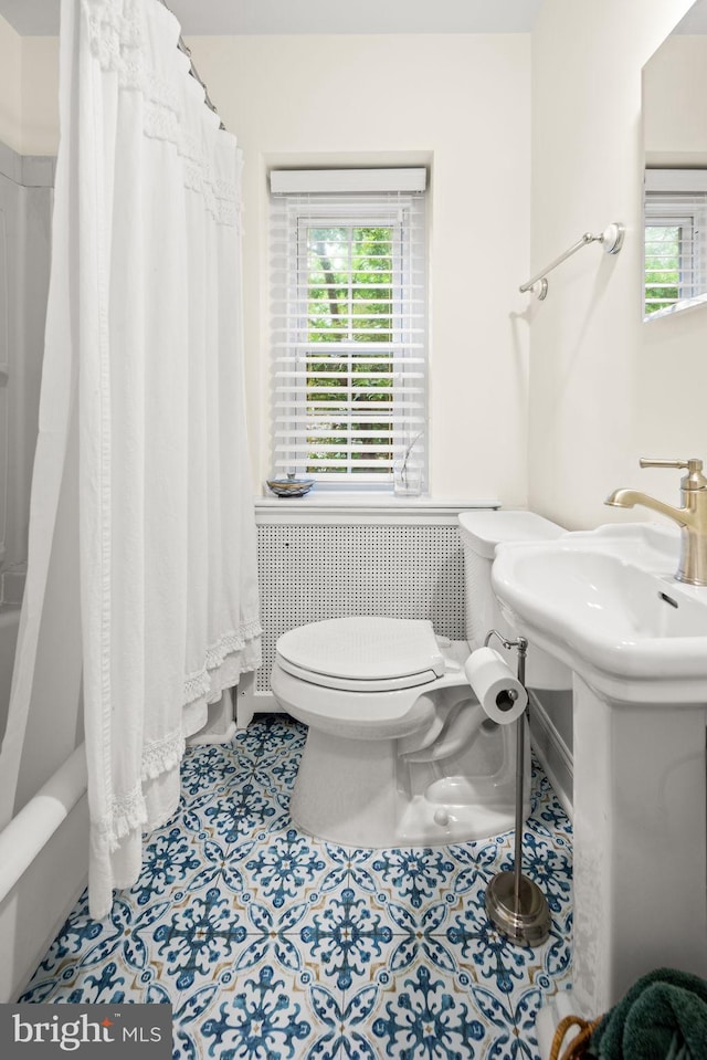 bathroom with toilet, plenty of natural light, radiator heating unit, and tile patterned floors