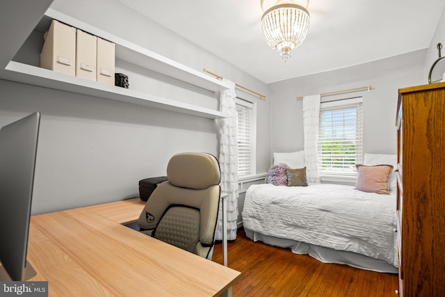 bedroom with a chandelier, wood finished floors, and a desk