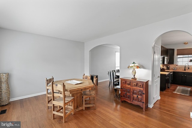5971 Schooner Cir, King George, VA 22485 - dining space featuring arched walkways, wood finished floors, and baseboards
