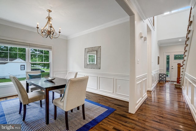 dining room featuring crown molding, dark wood-type flooring, a chandelier, a decorative wall, and a wainscoted wall