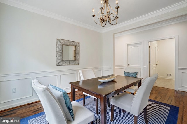dining area with a chandelier, hardwood / wood-style floors, a decorative wall, crown molding, and wainscoting