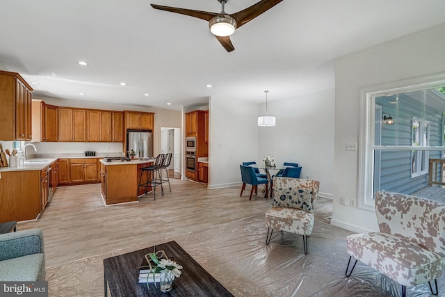 living room with a ceiling fan, recessed lighting, baseboards, and light wood-type flooring