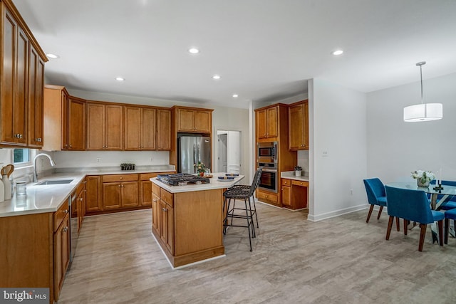 kitchen with appliances with stainless steel finishes, a sink, a breakfast bar area, brown cabinetry, and a center island