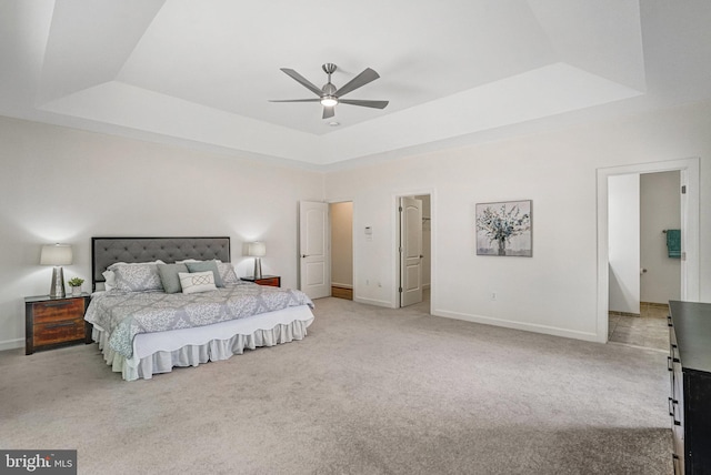bedroom featuring a tray ceiling, carpet floors, and baseboards