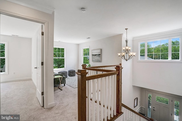 hall featuring an upstairs landing, light colored carpet, a chandelier, and baseboards