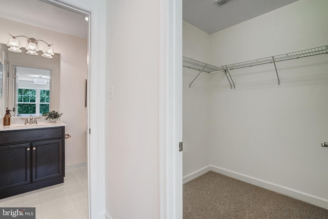 walk in closet with a sink and light colored carpet