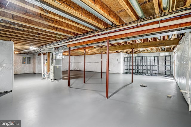 unfinished basement featuring heating unit and electric panel