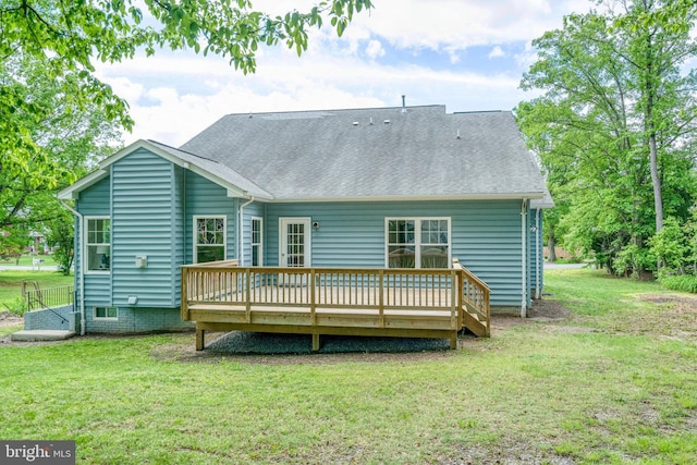 rear view of property featuring a deck, a yard, and roof with shingles