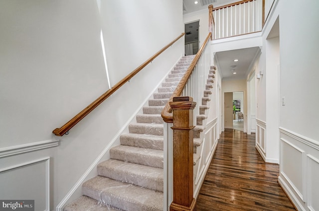 stairway featuring crown molding, wood finished floors, recessed lighting, and a wainscoted wall