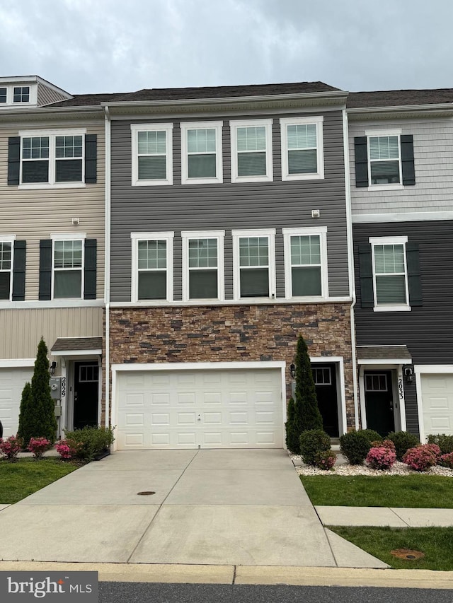 multi unit property with stone siding, driveway, and a garage