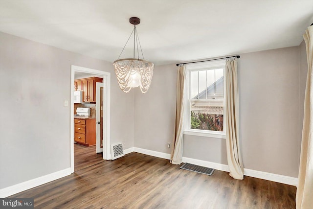 unfurnished dining area with an inviting chandelier, baseboards, dark wood-style floors, and visible vents