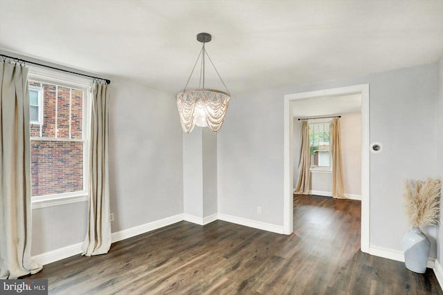 unfurnished dining area with baseboards, a notable chandelier, and dark wood-type flooring