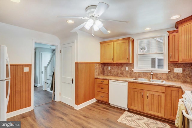 kitchen featuring a ceiling fan, white appliances, wainscoting, a sink, and light wood-type flooring