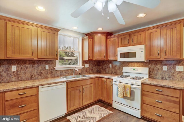 kitchen with white appliances, ceiling fan, a sink, wood finished floors, and tasteful backsplash