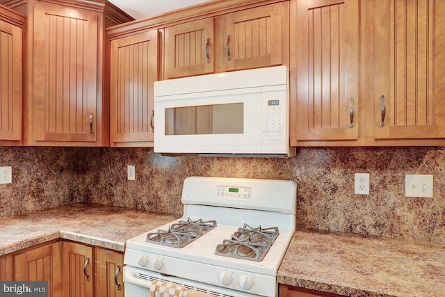 kitchen featuring backsplash, white appliances, and light countertops