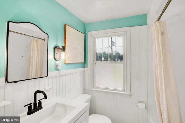 full bath featuring toilet, wainscoting, a shower with shower curtain, and vanity
