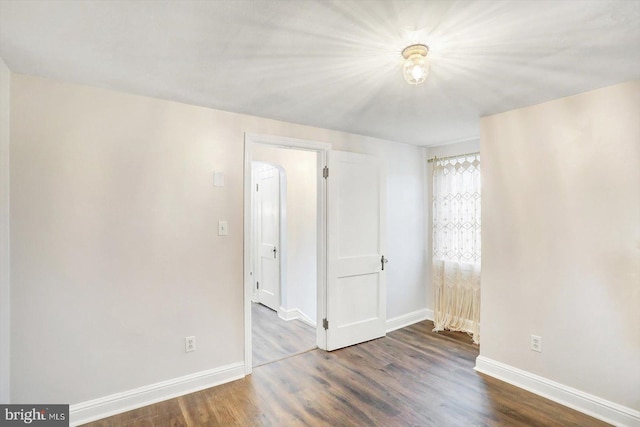spare room featuring wood finished floors and baseboards