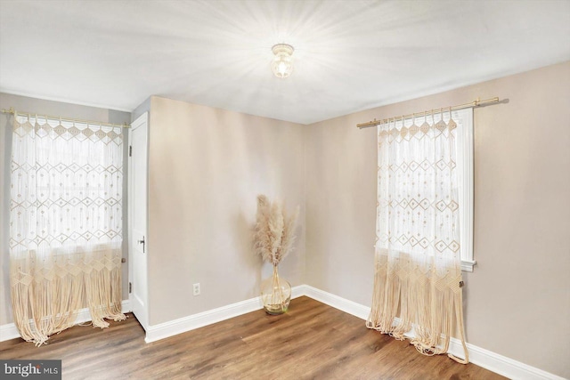 spare room featuring baseboards and wood finished floors