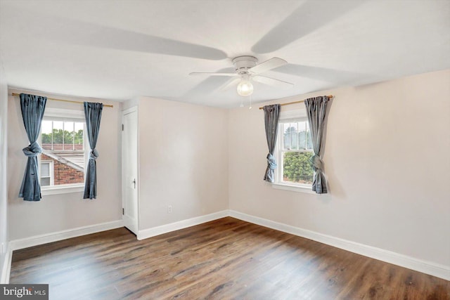 empty room featuring wood finished floors, baseboards, and a ceiling fan