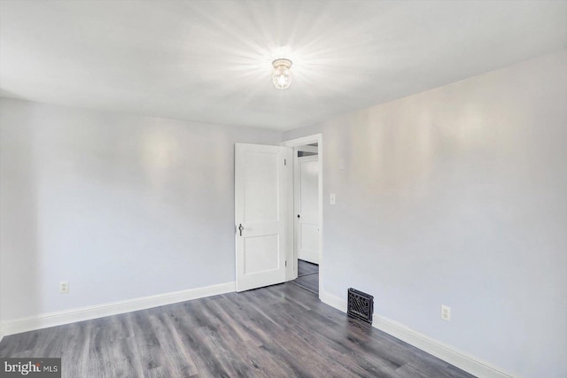 spare room with baseboards, visible vents, and wood finished floors