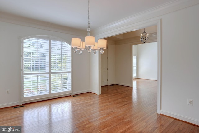 unfurnished dining area with a chandelier, healthy amount of natural light, light wood-style flooring, and crown molding