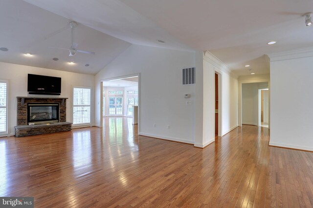 unfurnished living room with ceiling fan, wood-type flooring, a stone fireplace, baseboards, and high vaulted ceiling