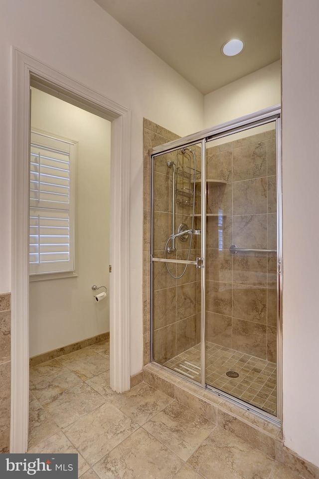 full bath featuring a stall shower and baseboards