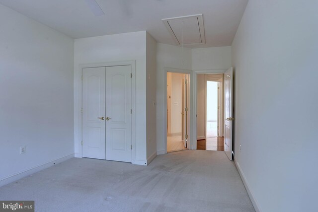 unfurnished bedroom featuring attic access, carpet flooring, a closet, and baseboards