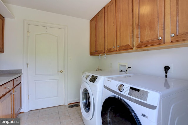 clothes washing area featuring washer and clothes dryer, cabinet space, and light tile patterned floors