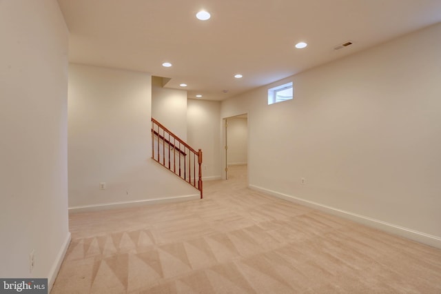 below grade area featuring recessed lighting, light colored carpet, baseboards, and stairway
