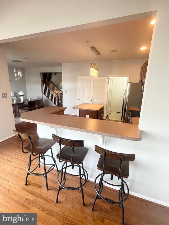 1716 Sunningdale Ln, Hanover, MD 21076 - kitchen featuring baseboards, wood finished floors, freestanding refrigerator, a breakfast bar, and decorative light fixtures
