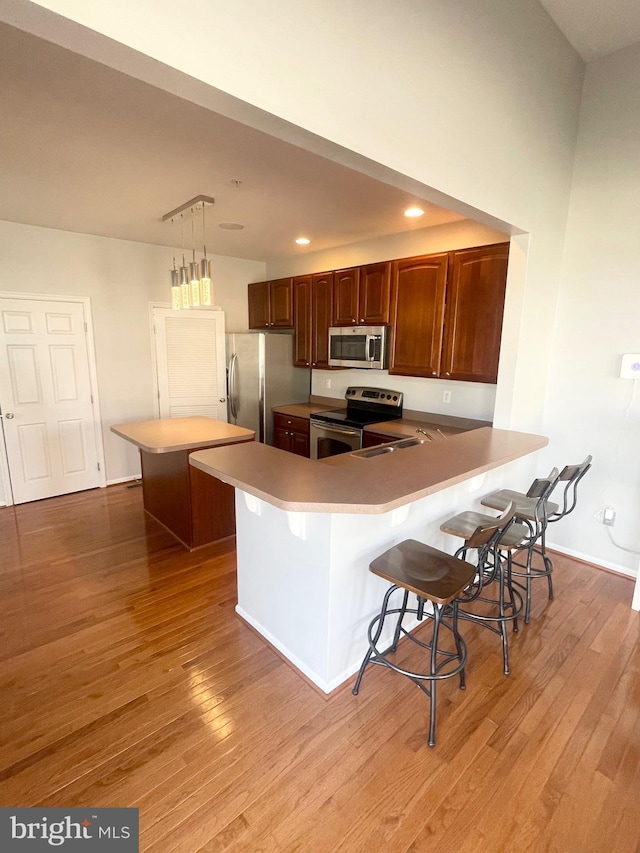 1716 Sunningdale Ln, Hanover, MD 21076 - kitchen featuring appliances with stainless steel finishes, light wood finished floors, a kitchen breakfast bar, a sink, and light countertops