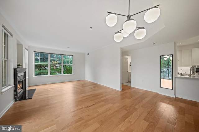 unfurnished living room featuring light wood finished floors, baseboards, and a lit fireplace