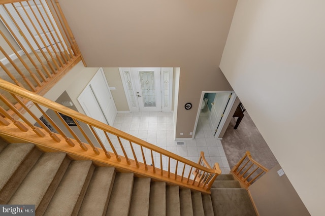 staircase with a high ceiling, baseboards, and tile patterned floors