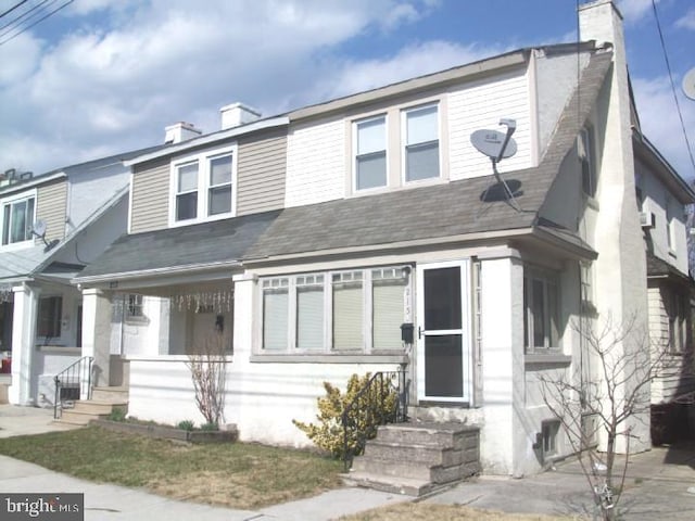 townhome / multi-family property with a porch, entry steps, a shingled roof, and a chimney