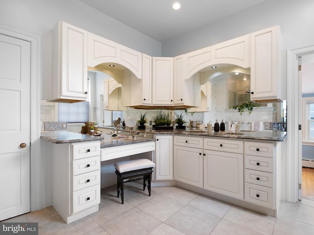 13 The Strand, New Castle, DE 19720 - kitchen featuring decorative backsplash, dark stone countertops, baseboard heating, and white cabinets