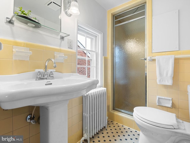 13 The Strand, New Castle, DE 19720 - bathroom featuring tile walls, radiator heating unit, a stall shower, a wainscoted wall, and toilet