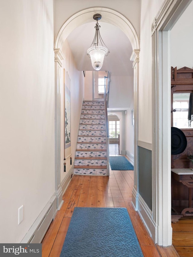 13 The Strand, New Castle, DE 19720 - hall with arched walkways, light wood-style flooring, stairway, decorative columns, and baseboards