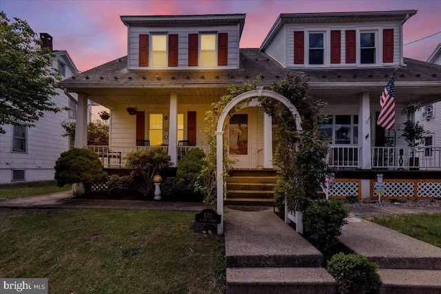 view of front of property featuring covered porch and a lawn